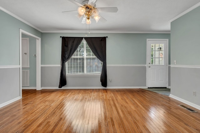 empty room with ceiling fan, light hardwood / wood-style floors, ornamental molding, and a healthy amount of sunlight