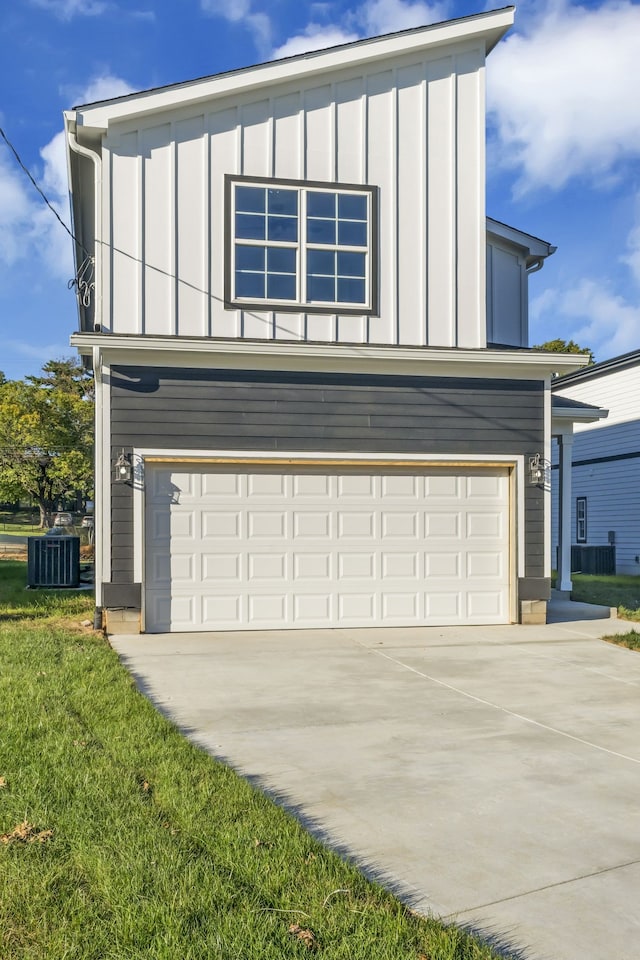 view of front of home with a garage, a front lawn, and central AC unit