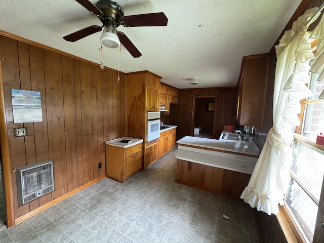 bathroom featuring wood walls, ceiling fan, heating unit, and a textured ceiling