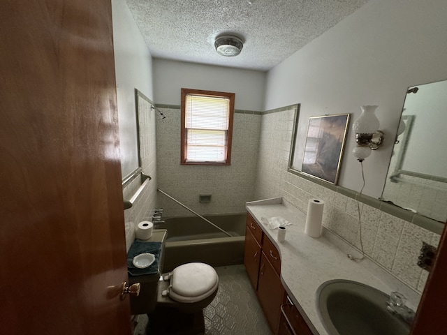 full bathroom with tiled shower / bath, vanity, a textured ceiling, tile walls, and toilet