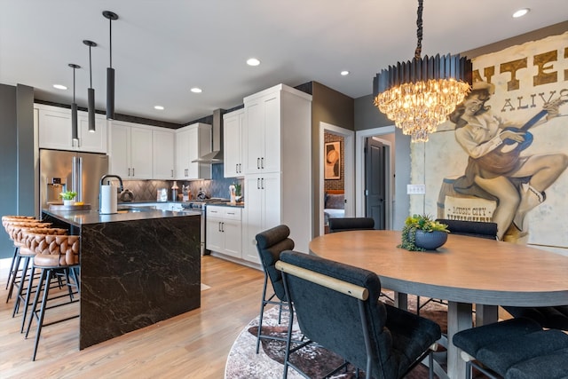 kitchen with decorative backsplash, white cabinets, pendant lighting, light hardwood / wood-style flooring, and appliances with stainless steel finishes