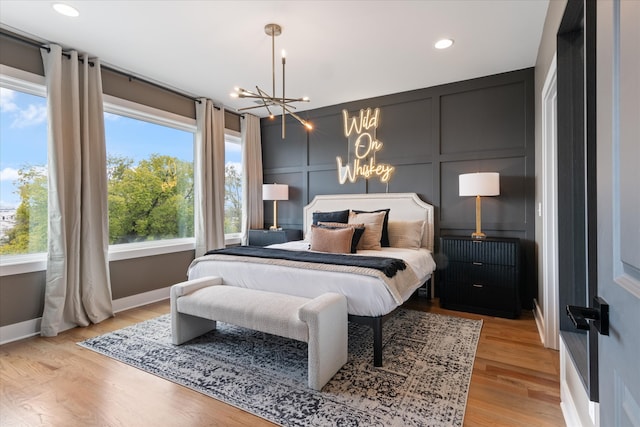 bedroom featuring an inviting chandelier, light hardwood / wood-style flooring, and multiple windows