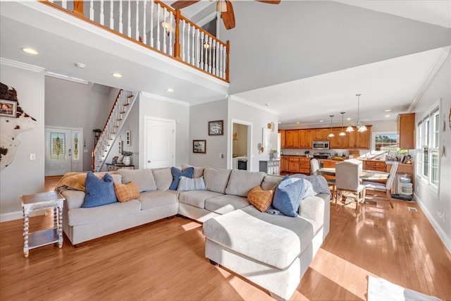 living room featuring ornamental molding, light hardwood / wood-style floors, and high vaulted ceiling