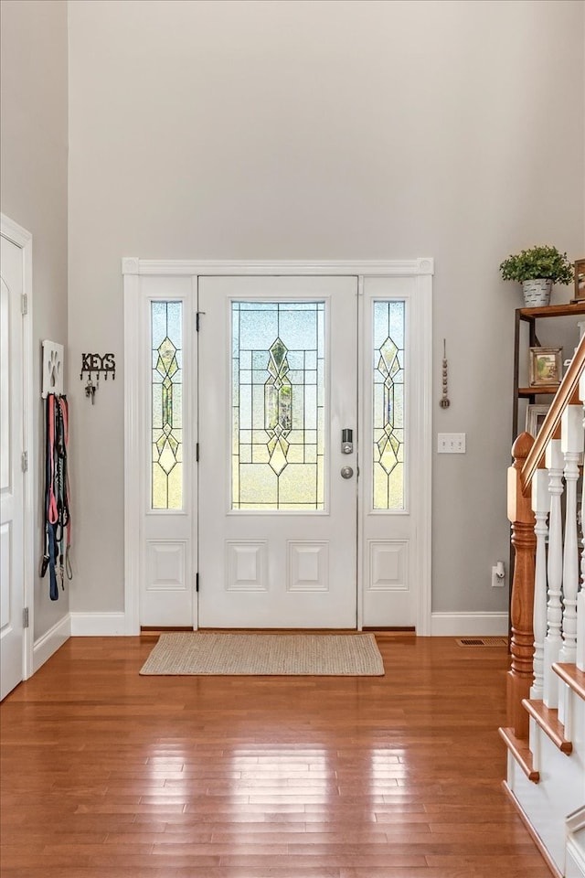 entryway with hardwood / wood-style floors and a high ceiling