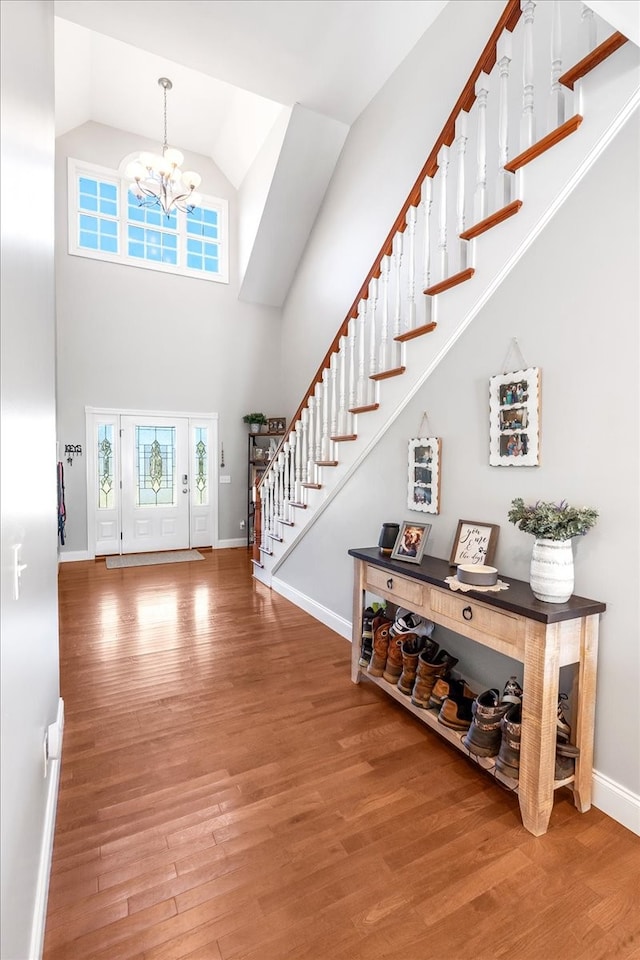 foyer entrance featuring high vaulted ceiling, a chandelier, and wood-type flooring