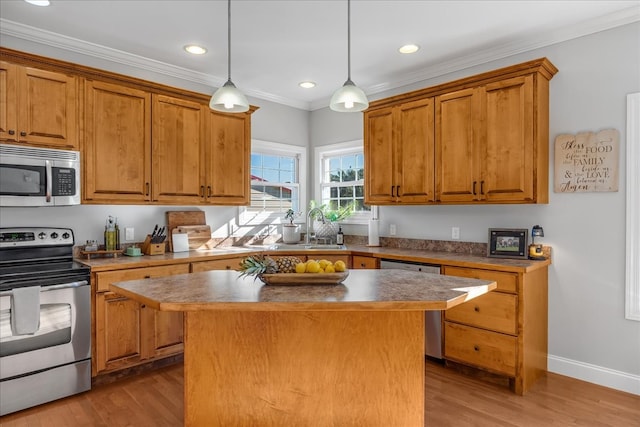 kitchen featuring light wood-type flooring, crown molding, hanging light fixtures, appliances with stainless steel finishes, and a center island