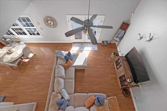 living room with a high ceiling, hardwood / wood-style flooring, and ceiling fan