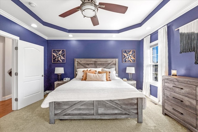 bedroom featuring a raised ceiling, light carpet, crown molding, and ceiling fan