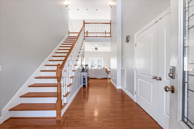 stairs featuring hardwood / wood-style flooring, ceiling fan, and a towering ceiling