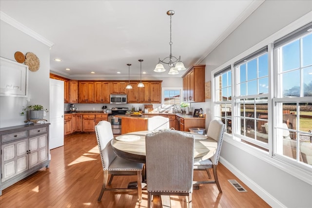 dining room with light hardwood / wood-style floors, crown molding, and an inviting chandelier