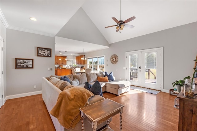 living room featuring crown molding, a wealth of natural light, french doors, and light hardwood / wood-style floors