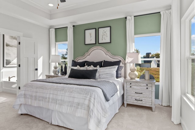 bedroom with ceiling fan, light colored carpet, and multiple windows