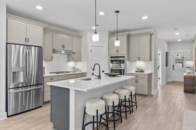 kitchen featuring light wood-type flooring, a kitchen bar, sink, and stainless steel appliances