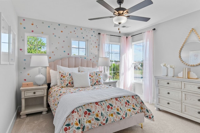 bedroom with multiple windows, ceiling fan, and light colored carpet