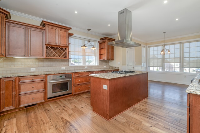 kitchen with island exhaust hood, a kitchen island, stainless steel appliances, and light wood-type flooring