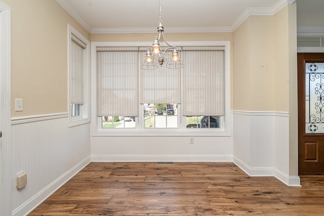 unfurnished dining area with ornamental molding, hardwood / wood-style floors, and an inviting chandelier