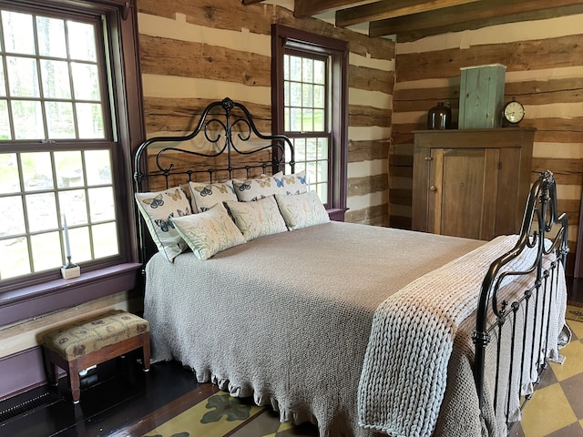 bedroom featuring hardwood / wood-style flooring, wood walls, beam ceiling, and multiple windows