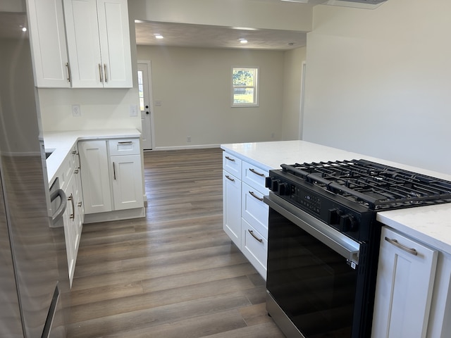 kitchen featuring appliances with stainless steel finishes, white cabinets, light stone counters, and light wood-type flooring