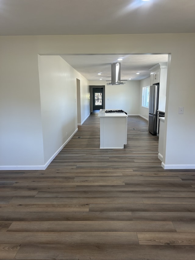 kitchen featuring a kitchen island, exhaust hood, dark wood-type flooring, stainless steel fridge, and white cabinetry