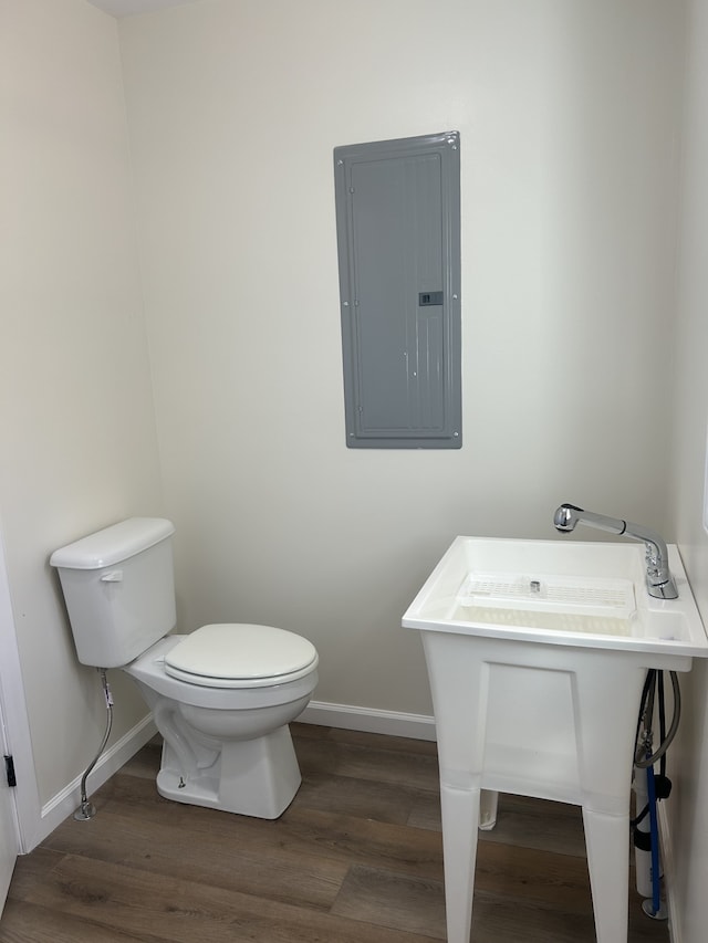 bathroom with toilet, wood-type flooring, and electric panel