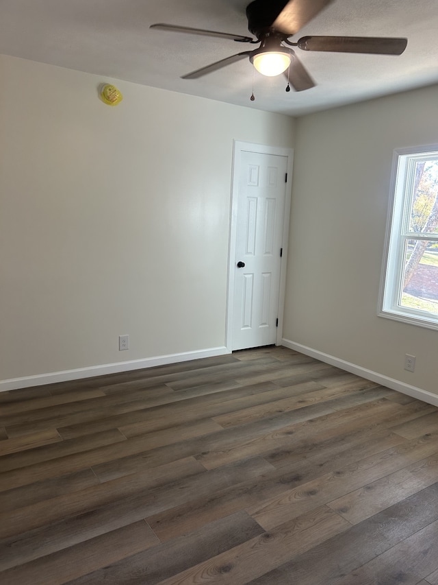 empty room featuring dark wood-type flooring and ceiling fan