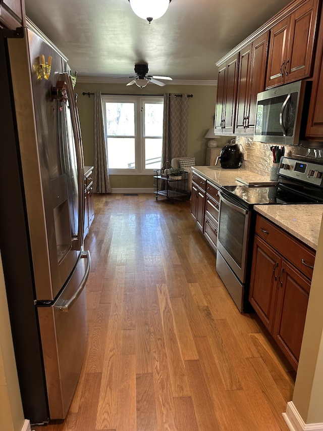 kitchen featuring light hardwood / wood-style floors, ceiling fan, tasteful backsplash, stainless steel appliances, and ornamental molding