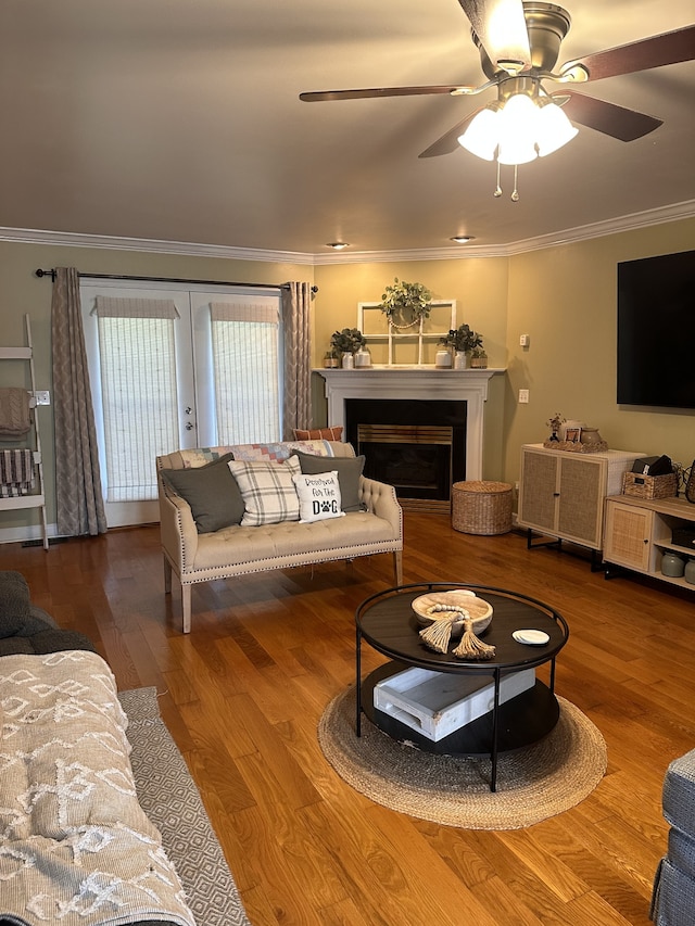 living room with wood-type flooring, ornamental molding, and ceiling fan