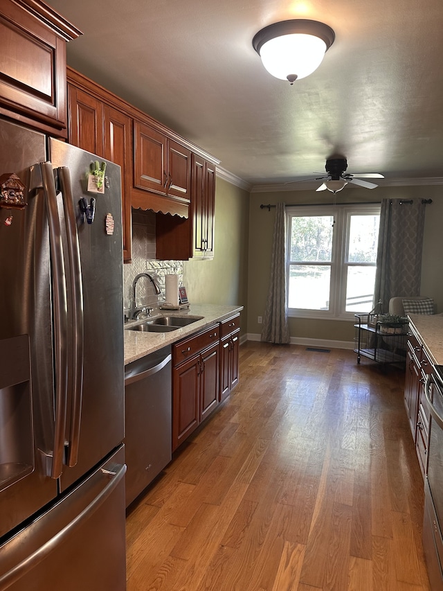 kitchen with appliances with stainless steel finishes, hardwood / wood-style flooring, sink, and ornamental molding