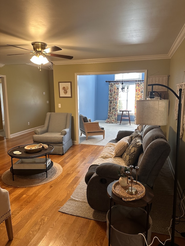 living room with ceiling fan with notable chandelier, light wood-type flooring, and crown molding