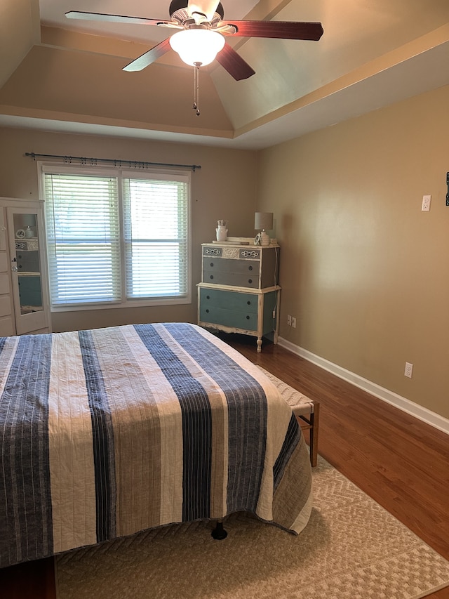 bedroom with a raised ceiling, hardwood / wood-style floors, and ceiling fan