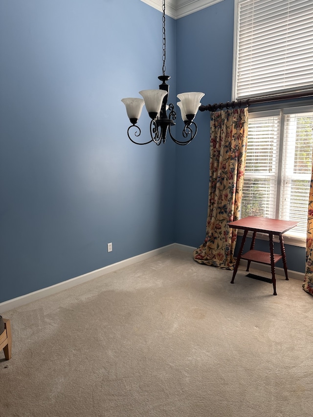 carpeted spare room with ornamental molding and a chandelier