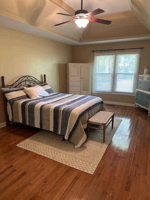 bedroom featuring a tray ceiling, dark hardwood / wood-style flooring, and ceiling fan