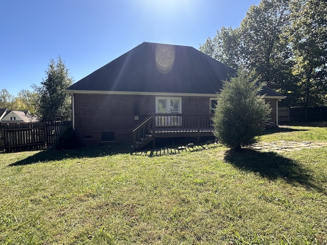 rear view of property featuring a deck and a lawn