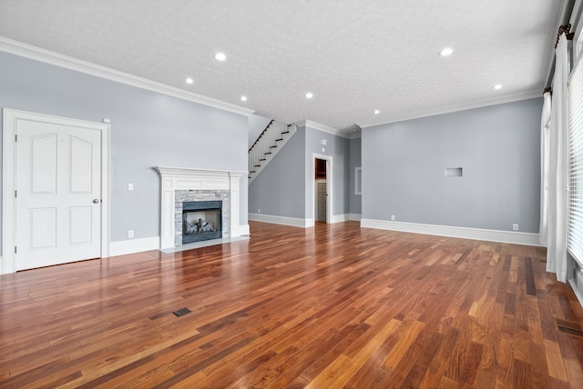 unfurnished living room featuring crown molding, a stone fireplace, hardwood / wood-style floors, and a textured ceiling