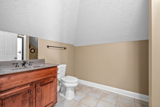 bathroom with vaulted ceiling, vanity, toilet, and tile patterned floors