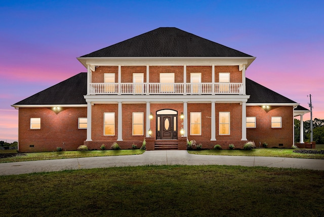 view of front of house featuring a balcony and a lawn