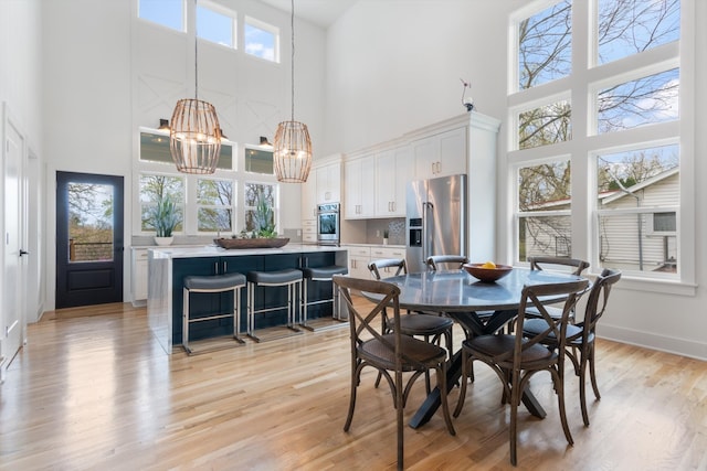 dining room featuring light hardwood / wood-style flooring, a high ceiling, an inviting chandelier, and a wealth of natural light