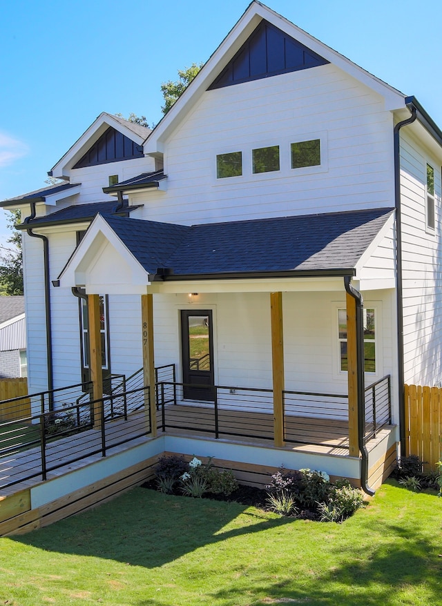 rear view of property featuring a yard and covered porch