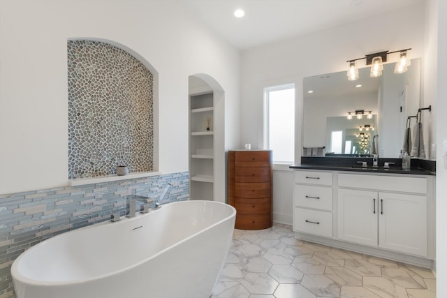 bathroom featuring backsplash, a tub to relax in, and vanity