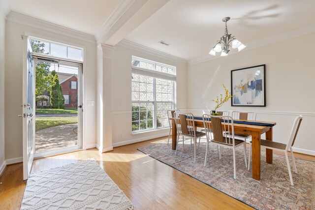 dining area featuring a notable chandelier, light wood-type flooring, crown molding, and plenty of natural light