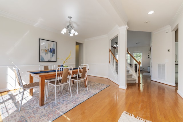 dining area featuring an inviting chandelier, light hardwood / wood-style floors, ornamental molding, and decorative columns