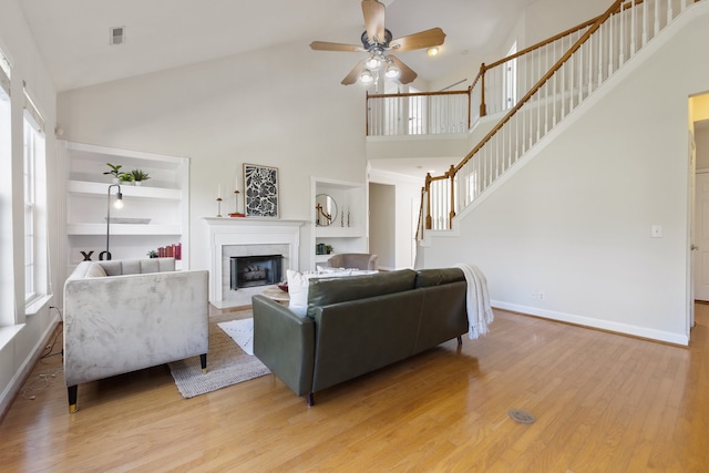 living room featuring light wood-type flooring, high vaulted ceiling, and a healthy amount of sunlight