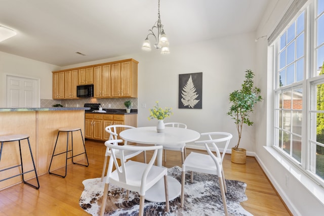 dining room with plenty of natural light, an inviting chandelier, and light hardwood / wood-style flooring