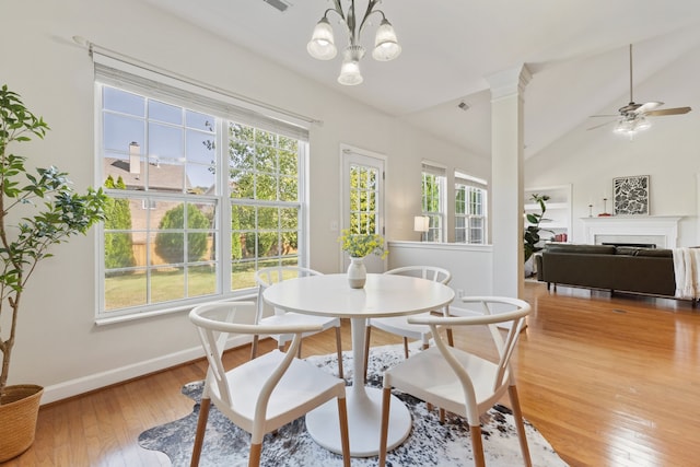 dining room featuring ceiling fan with notable chandelier, hardwood / wood-style floors, and vaulted ceiling