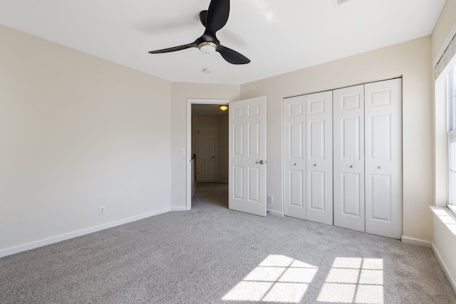 unfurnished bedroom featuring ceiling fan, a closet, and light carpet