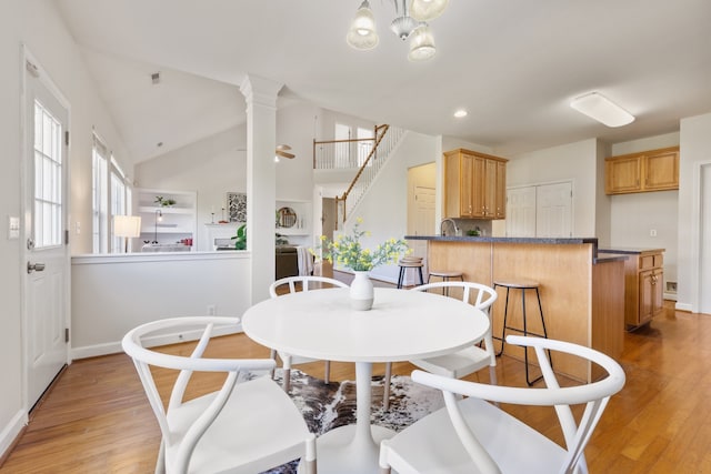 dining area featuring ornate columns, an inviting chandelier, lofted ceiling, and light hardwood / wood-style floors