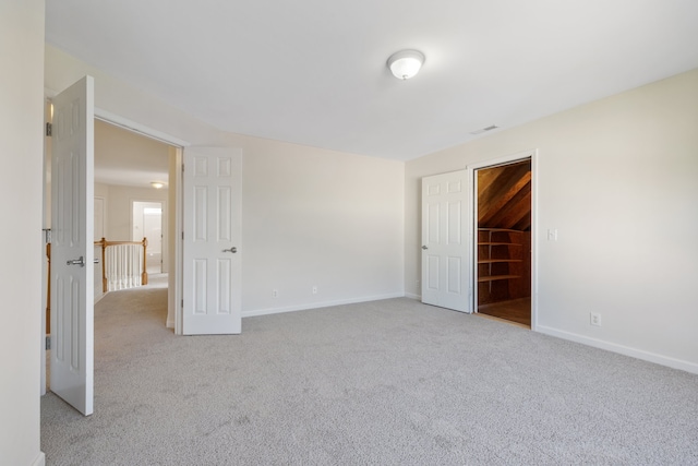 unfurnished bedroom with a spacious closet, a closet, and light colored carpet