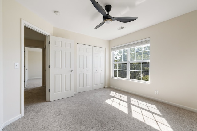 unfurnished bedroom with ceiling fan, light colored carpet, and a closet