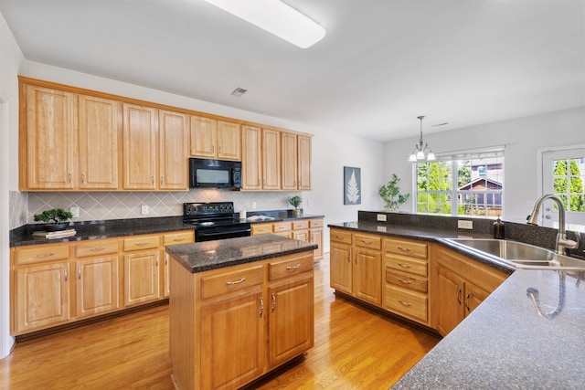 kitchen with light wood-type flooring, black appliances, a center island, sink, and hanging light fixtures