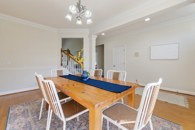 dining room with an inviting chandelier, hardwood / wood-style flooring, crown molding, and ornate columns